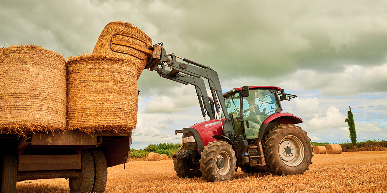 Tractor lifting bales on farm